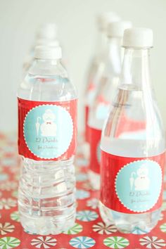 three bottles of water sitting on top of a red and blue tablecloth with flowers