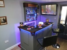 a bar with two stools in front of it and a television on the wall