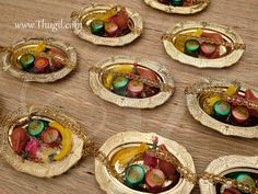 there are many small gold trays with colorful items in them on the table next to each other