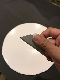 a person holding a knife in front of a white circle on a black table top