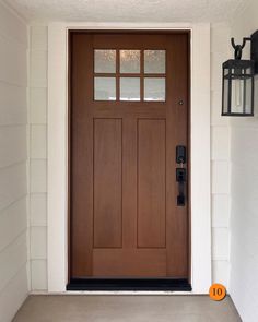 the front door is brown and has two lanterns on it's side walk way