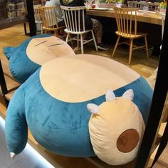 a large blue stuffed animal laying on top of a wooden floor next to two chairs