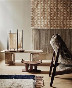 a wooden chair sitting next to a table on top of a hard wood floor covered in rugs