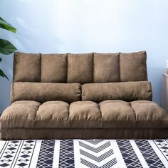 a couch sitting on top of a rug next to a plant