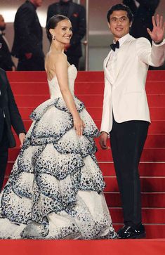 a man in a tuxedo waves to the crowd as he walks down stairs