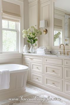 a bathroom with a tub, sink and large mirror in it's center area