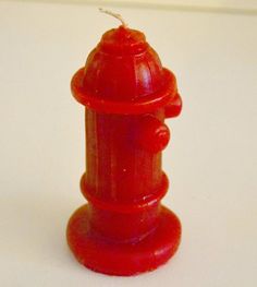 a red toy fire hydrant sitting on top of a white table next to a wall