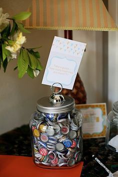 there is a jar full of bottle caps on the table with a note attached to it