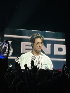 a man standing in front of a large screen on top of a stage with headphones