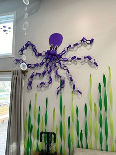 a purple octopus is hanging on the wall next to green and white streamers in front of a window