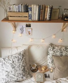 a bed with pillows and books on top of it next to a shelf filled with books