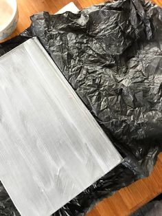 a wooden table topped with black plastic bags and a white plate on top of it