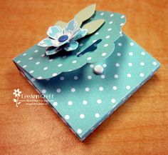 an origami flower on top of a polka dot paper bag with buttons and pearls