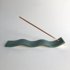 a toothbrush holder with a wooden stick sticking out of it's mouth, on a white surface