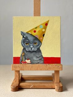 a painting of a cat with a party hat on it's head sitting in front of a easel