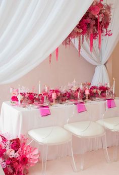 a long table with pink flowers and candles on it is set up for a party