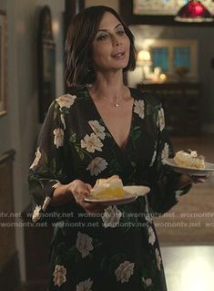 a woman in a floral dress holding a plate with food on it and looking up