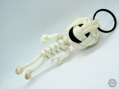 a white and black knot is attached to a keychain on a white background