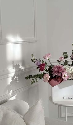 a vase filled with pink and white flowers on top of a table next to a couch