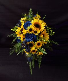 a bouquet of sunflowers and blue roses in a vase on a black background