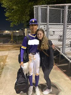 two people standing next to each other in baseball uniforms