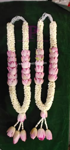 two pink and white flowers are attached to the same necklaces on a green background