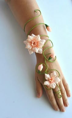 a person's hand with flowers on it and green string attached to the wrist