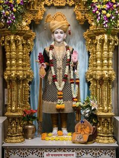 a statue of the hindu god in front of an altar with flowers and other decorations