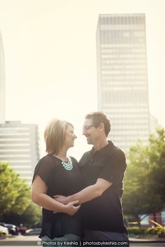 a man and woman standing together in front of tall buildings