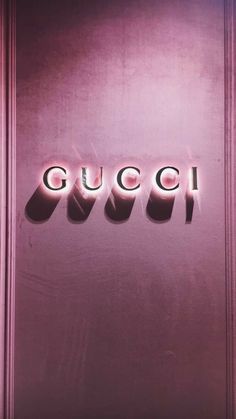 the word gucci spelled in cursive letters on a purple door with pink lighting