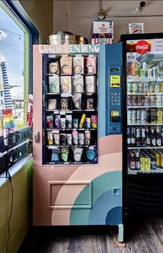 a vending machine with drinks and snacks in it's display case next to a window