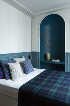 a bed in a bedroom with blue walls and plaid pillows on the headboard,