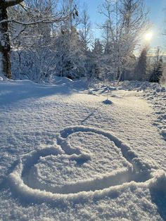 a snow covered field with trees in the background and a smiley face drawn in the snow