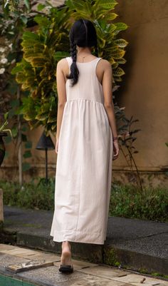 a woman in a white dress is walking down the street with her back to the camera