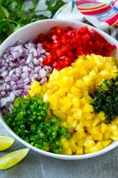 a bowl filled with chopped up vegetables next to sliced limes and cilantro