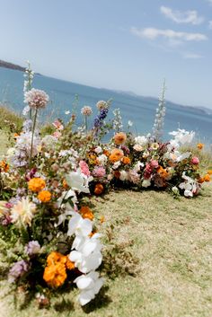 an arrangement of flowers on the grass by the water