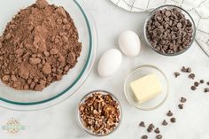 ingredients to make chocolate chip cookies laid out on a white counter top, including eggs, butter and chocolate chips