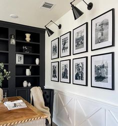 black and white photographs hang on the wall above a wooden table