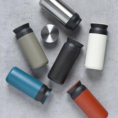 thermos are lined up next to each other in different colors and sizes on a gray surface