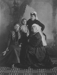 an old black and white photo of three women sitting at a table with a book