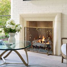 a living room with a glass table and fire place