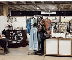 a clothing store with clothes on display in front of the counter and other items for sale