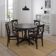 a dining room table with four chairs and a rug on the floor in front of it