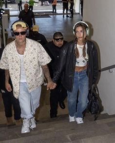 two people holding hands while walking down an escalator with other people in the background