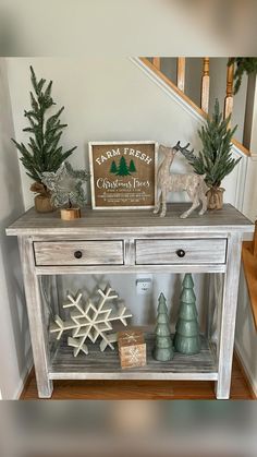 a christmas display on top of a wooden table in a room with stairs and trees