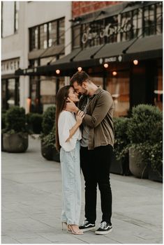 a man and woman standing next to each other in front of a building