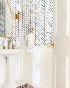 a white sink sitting under a bathroom mirror next to a wall mounted faucet