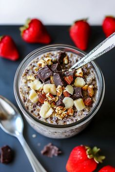 a bowl of oatmeal with nuts and chocolate on the side next to strawberries