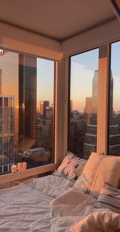 a bed sitting next to two large windows in a bedroom under a sky scraper