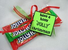 three candy bars wrapped in red ribbon tied to a green sign that says have a holly jolly christmas